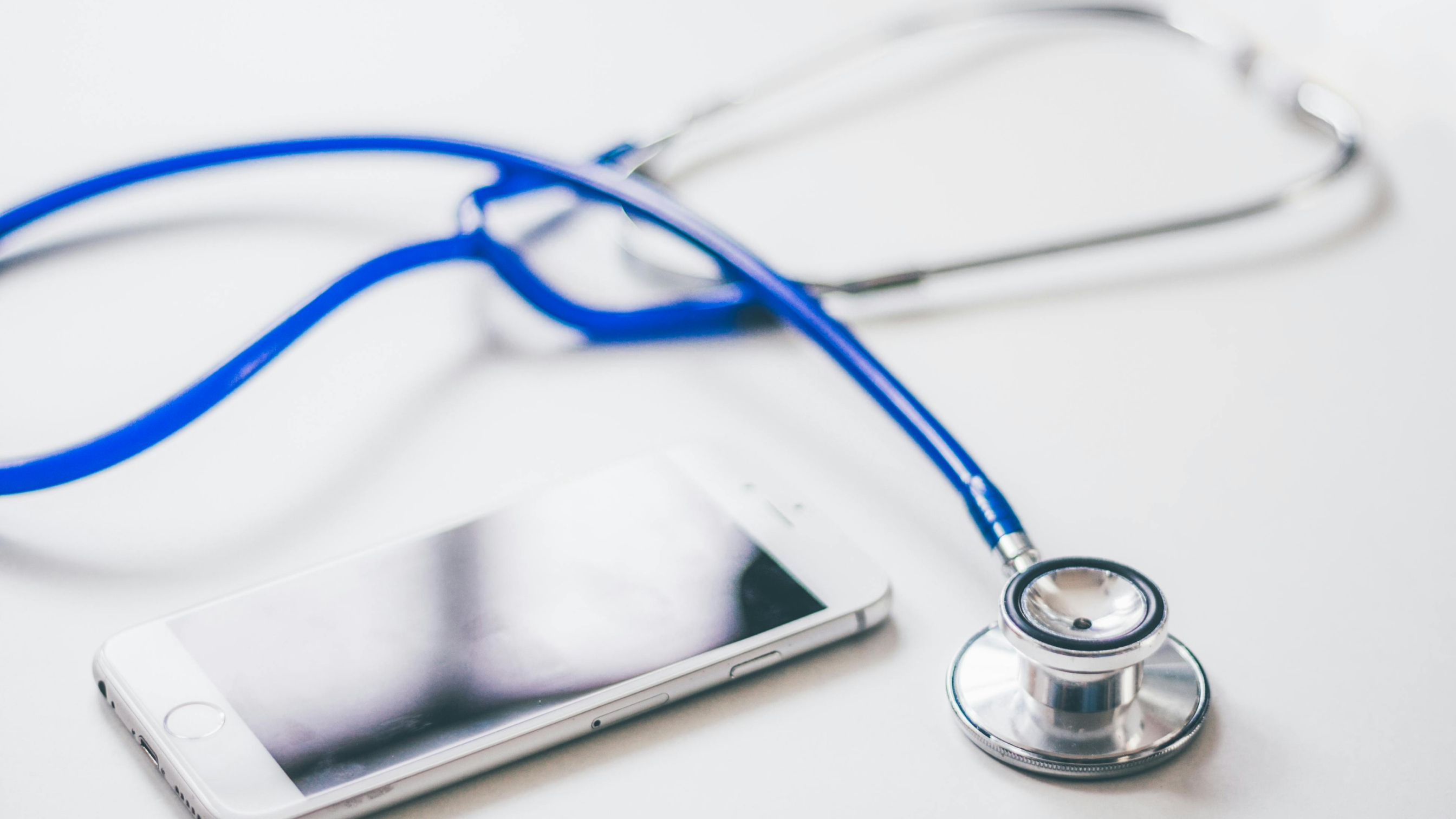 A stethoscope lying on a white surface next to other medical tools, symbolizing healthcare or medical technology.