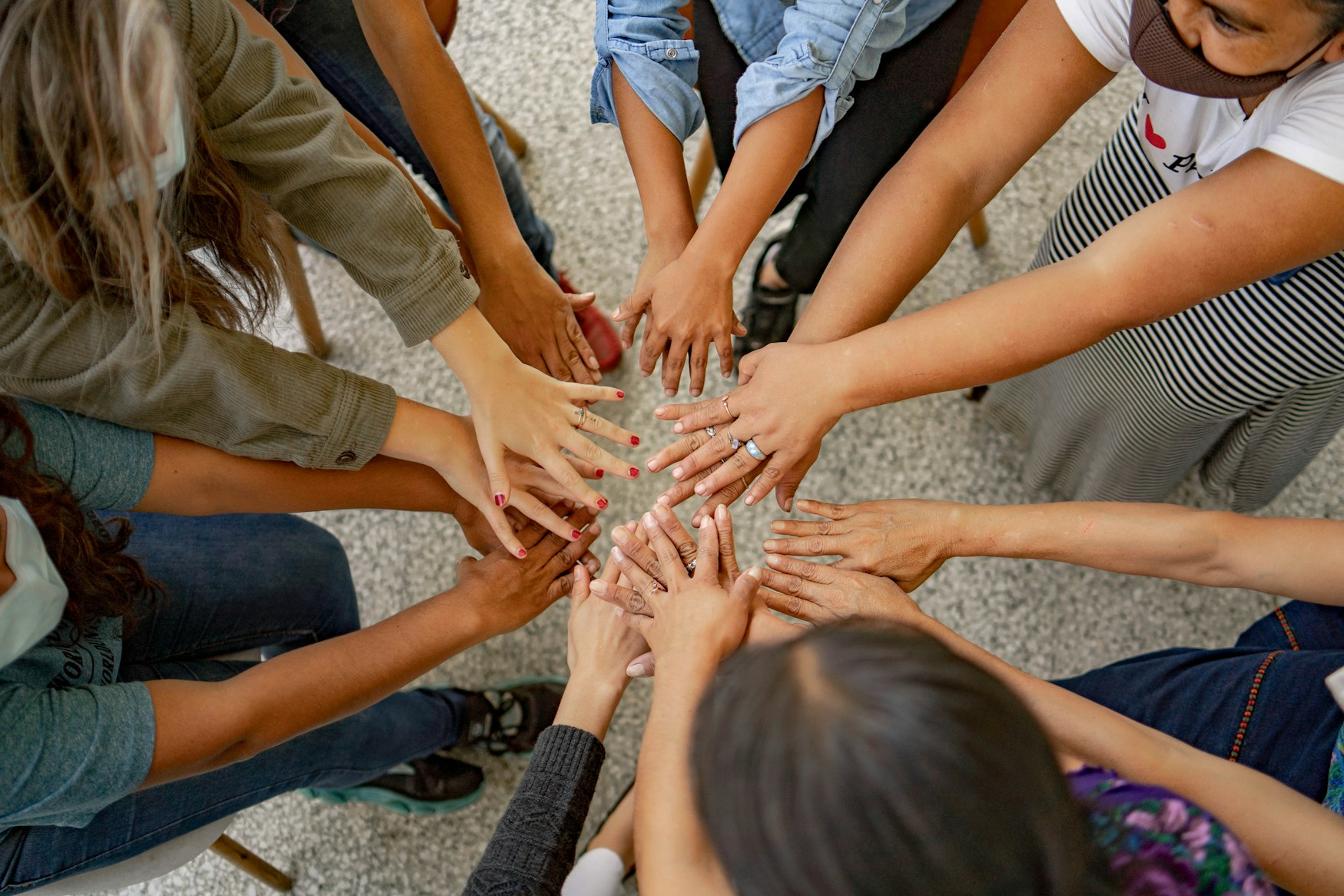 People standing in a circle and stretching their hands forward