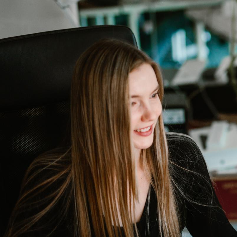 A designer sitting in an armchair, looking at the monitor with a smile on her face