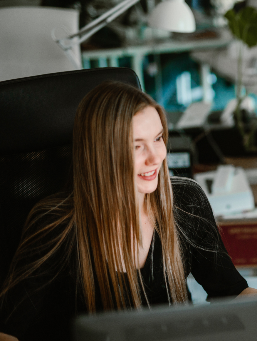 A designer sitting in an armchair, looking at the monitor with a smile on her face